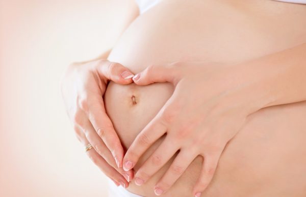 Pregnant Woman holding hands in a heart shape on her baby bump